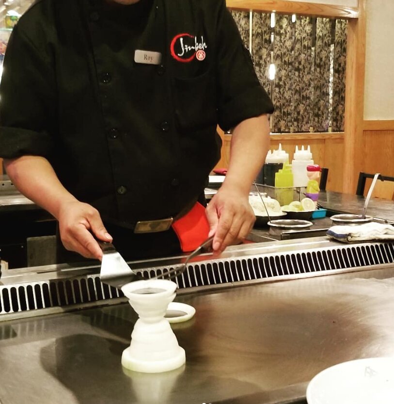 Hibachi chef performing the famous onion volcano at Jinbeh Lewisville