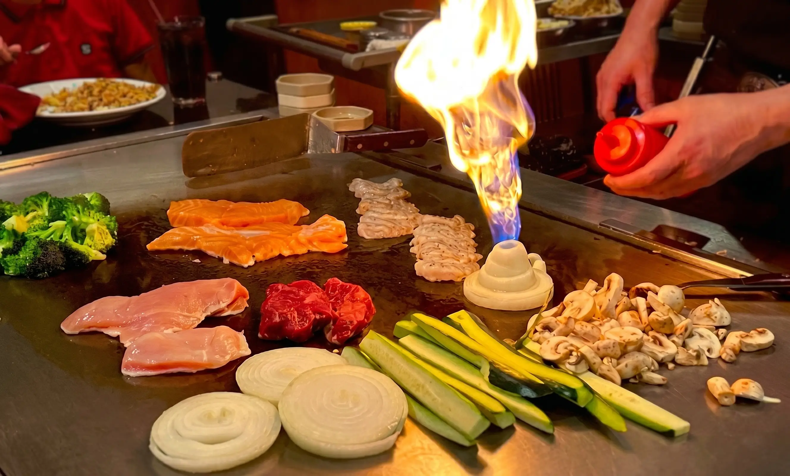 Onion volcano eruption with flames and sizzling vegetables on a hibachi grill at Jinbeh Japanese Restaurant