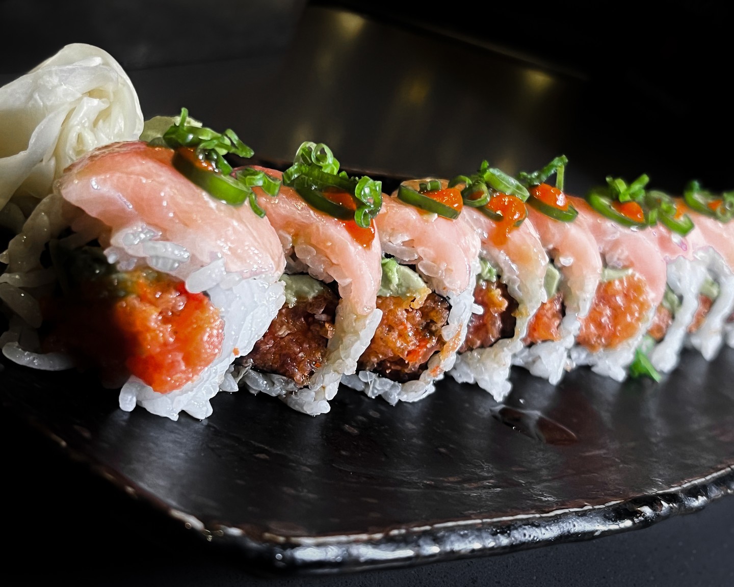 Fresh salmon topped specialty roll with jalapeΓ±o and tobiko at Jinbeh