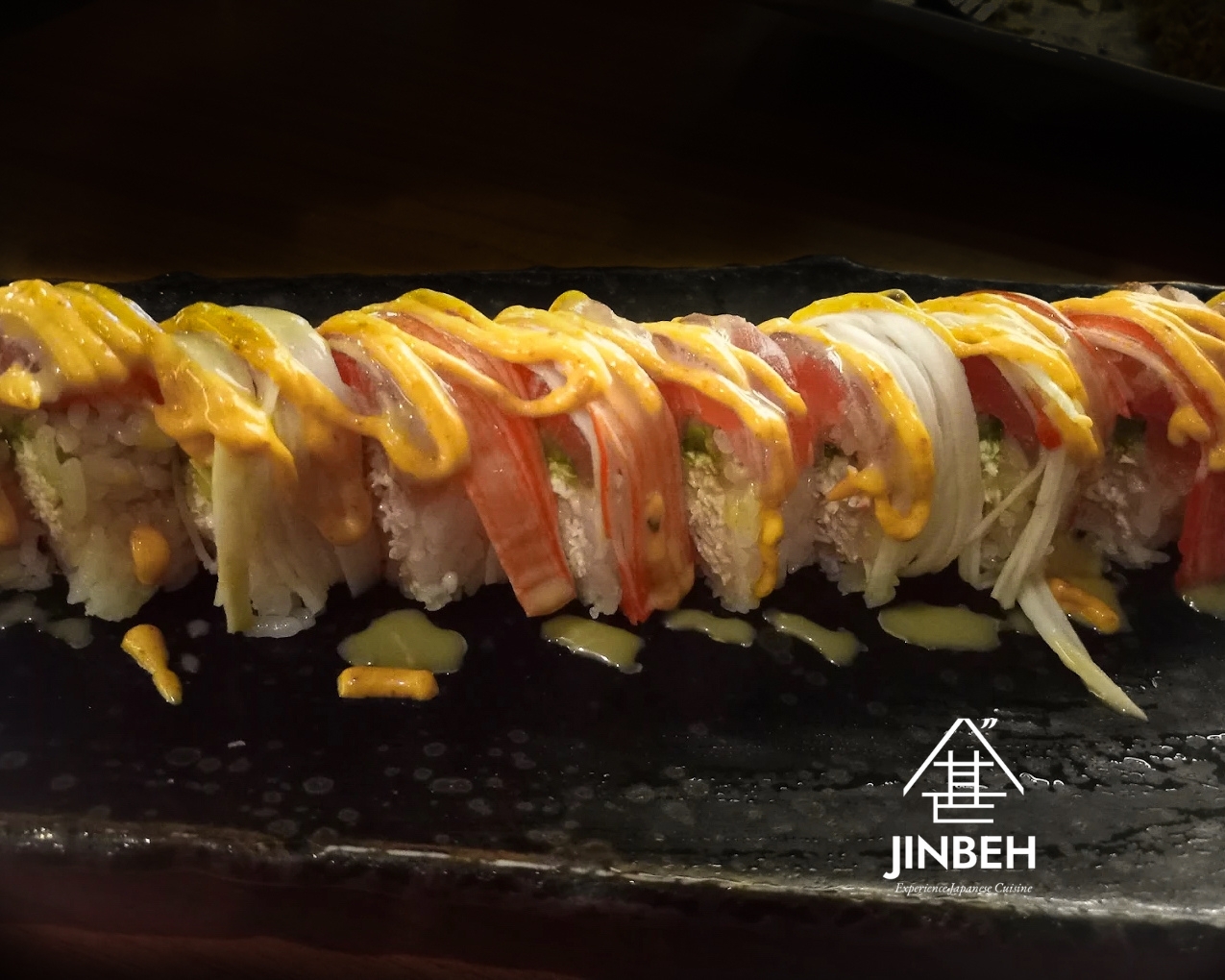 Rainbow specialty sushi roll with spicy mayo drizzle at Jinbeh Japanese Restaurant