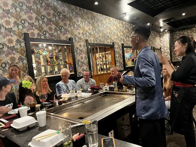 Family and friends celebrating a birthday party together around a hibachi table at Jinbeh Japanese Restaurant